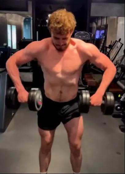 a shirtless man is lifting dumbbells in a gym .