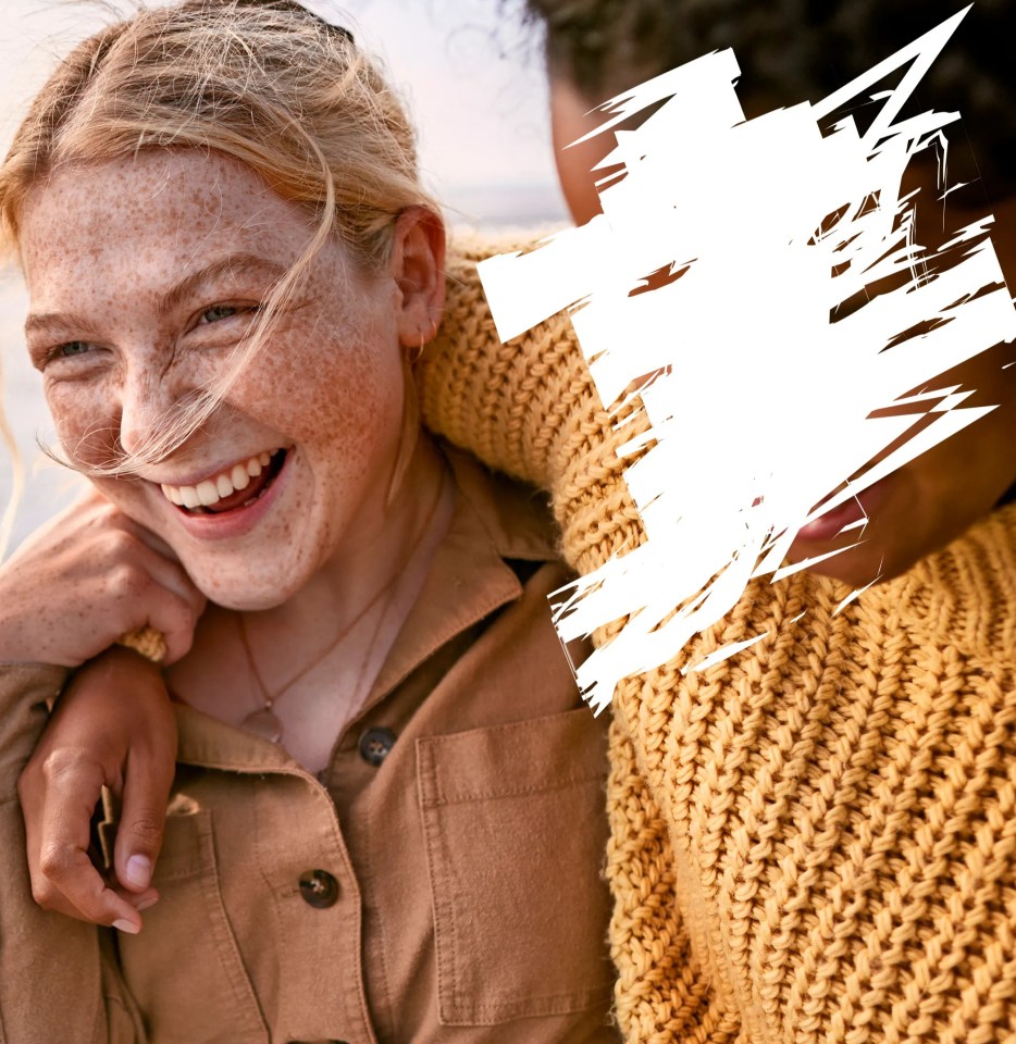 a woman with freckles smiles while a man holds her shoulder