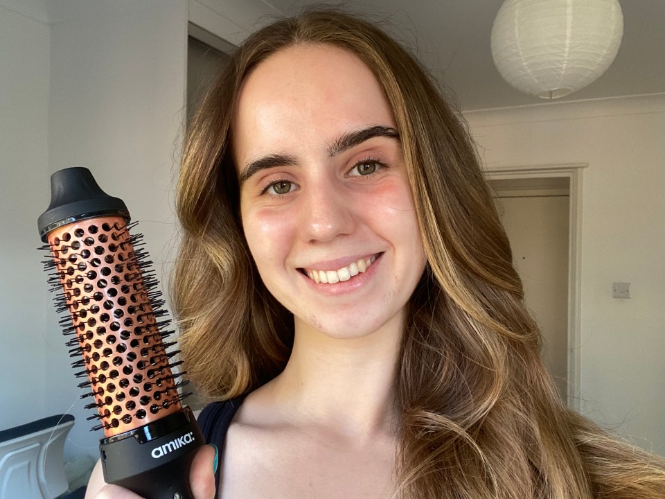 Woman holding a rose gold Amika hair brush.