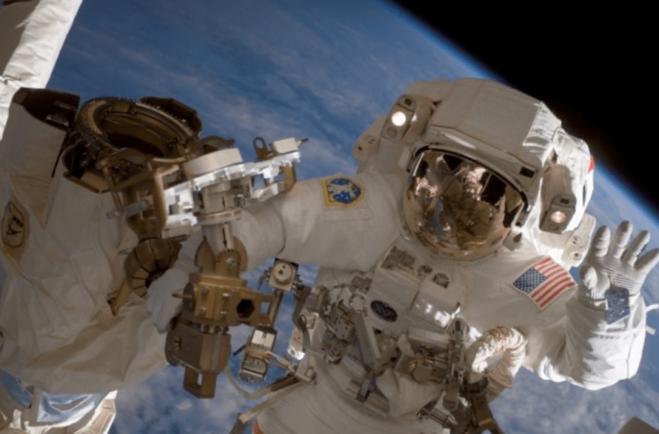 a man in an american space suit is waving at the camera