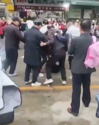 a group of people are standing on the side of a street .