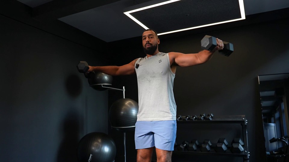 a man is lifting a dumbbell in a gym