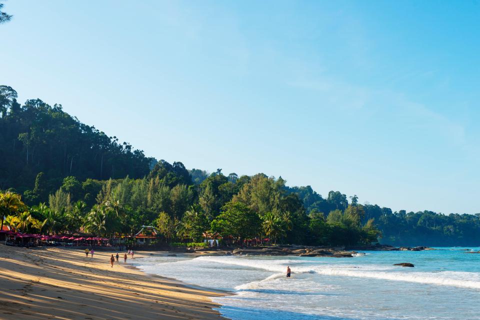 a beach with a few people walking on it