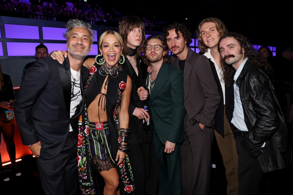 a group of people posing for a picture including a woman in a floral dress