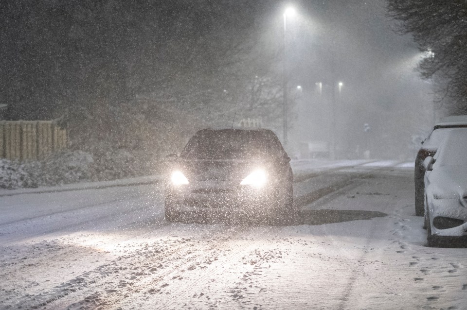 a car is driving down a snowy road at night
