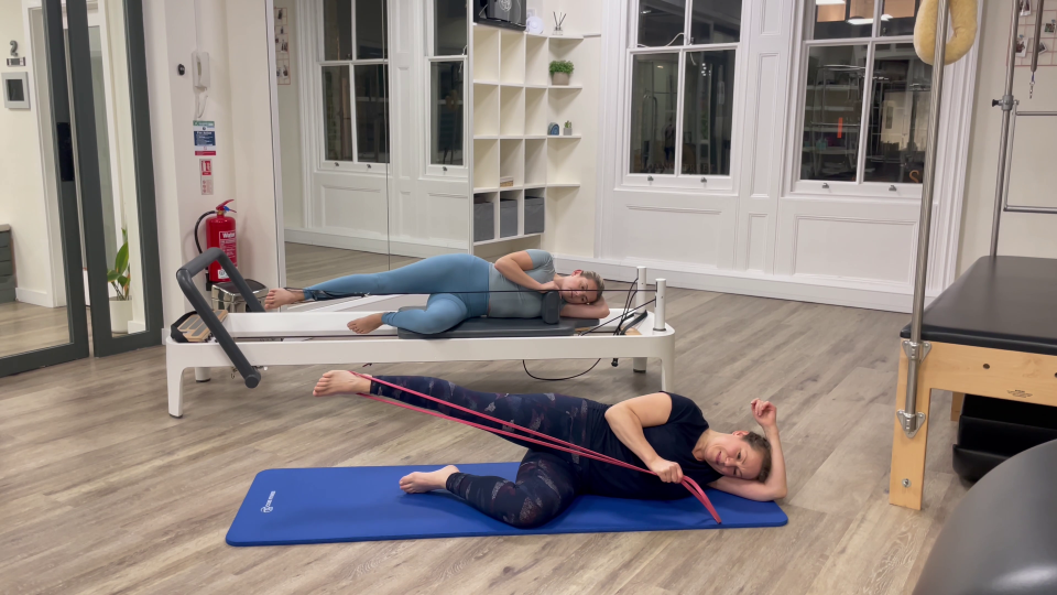 Two women performing Pilates exercises using resistance bands.