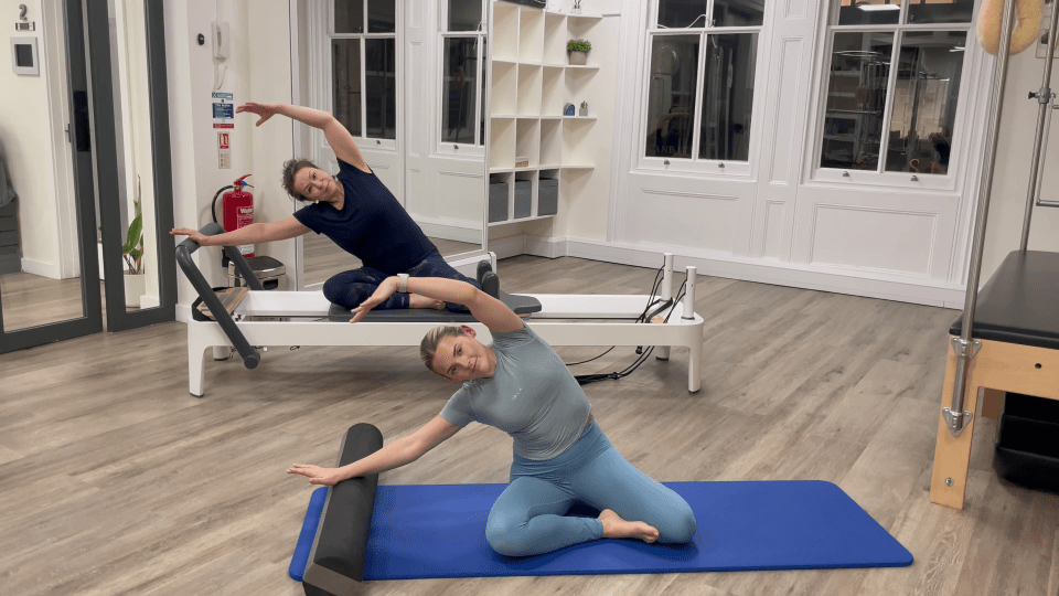 Two women performing Pilates exercises on a mat and reformer.