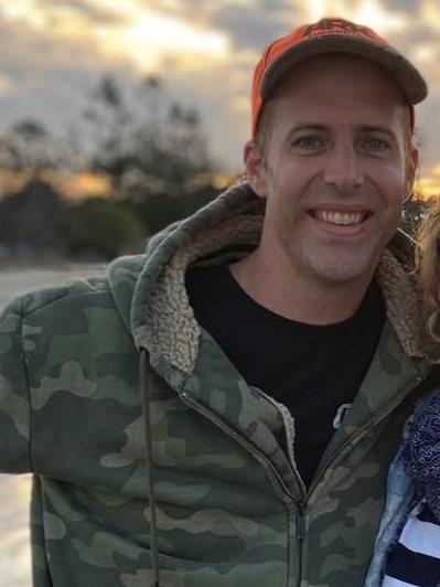 Man in camouflage hoodie and orange hat.