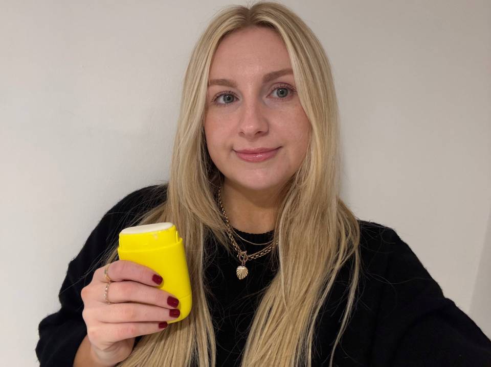 Woman holding yellow deodorant stick.