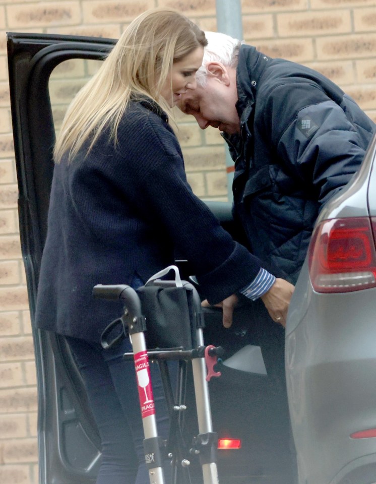 Woman helping man with walker into car.