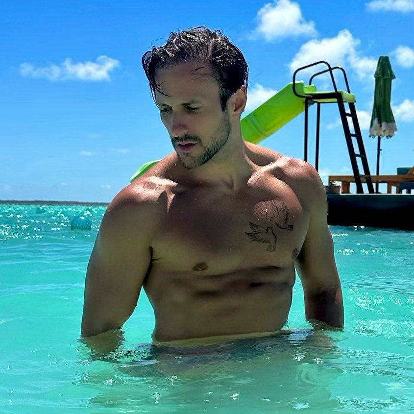 Shirtless man with chest tattoo in clear water.