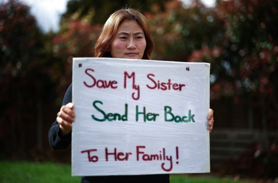 Woman holding a sign that reads, "Save My Sister Send Her Back To Her Family!"