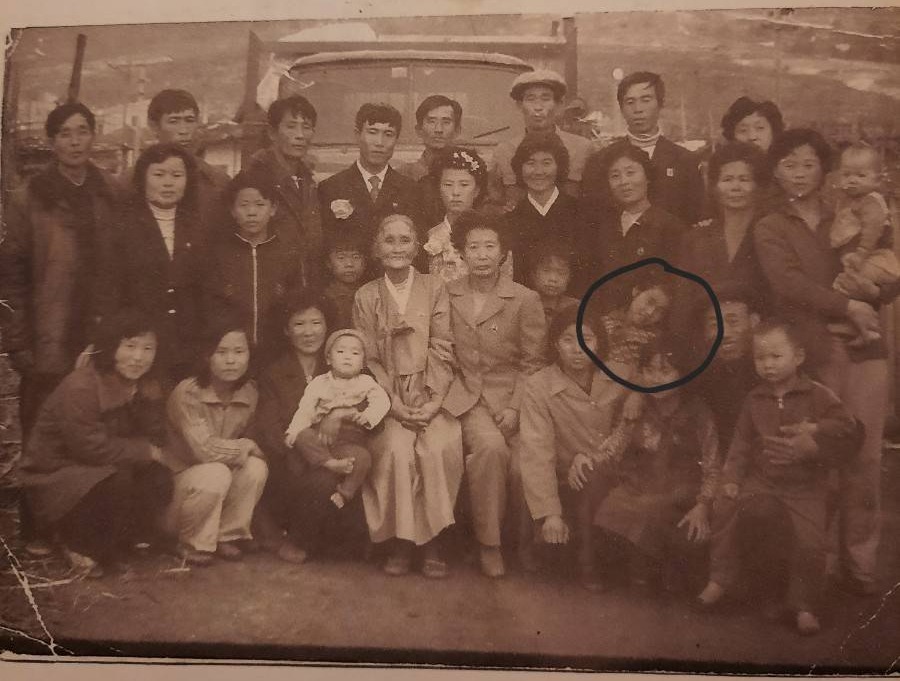 Large group photo of people, possibly a family, posing in front of a vehicle.