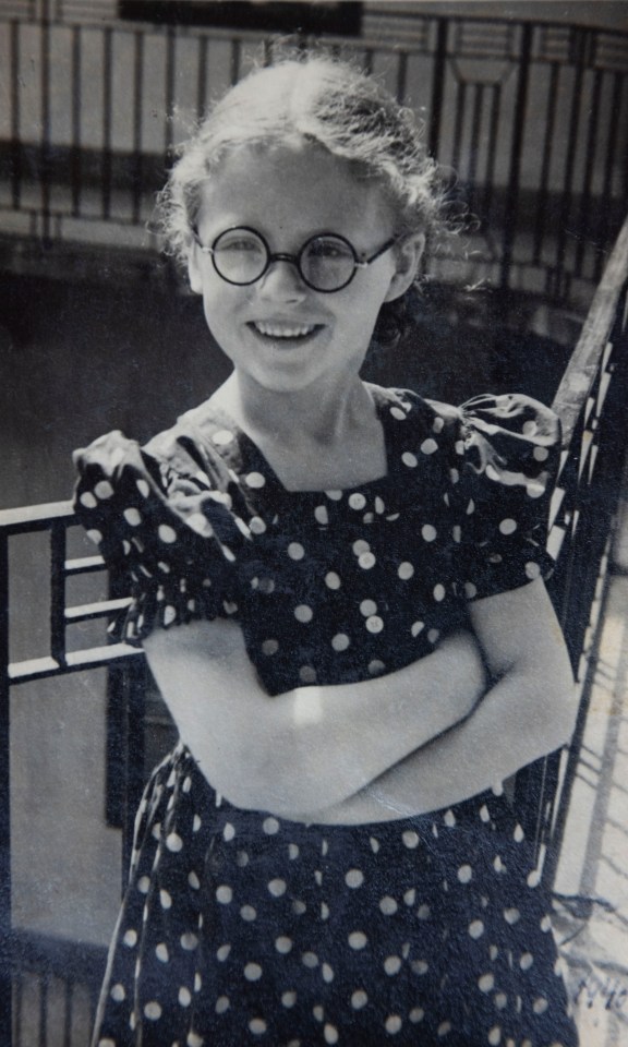 Black and white photo of a young girl wearing a polka dot dress and glasses.