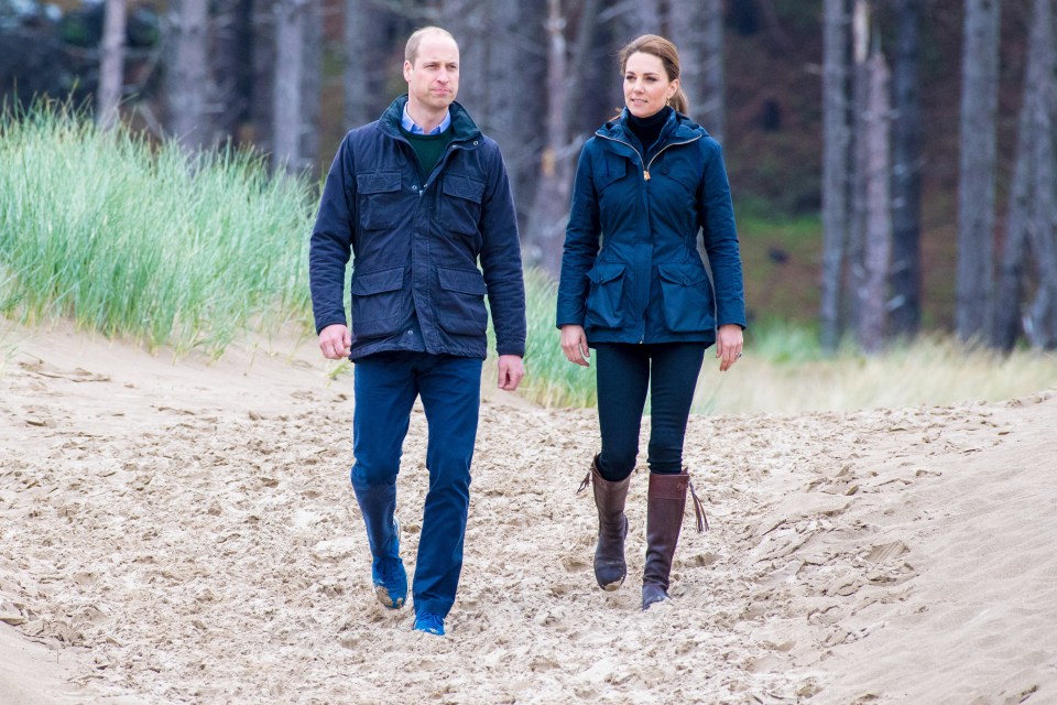 Prince William and Catherine, Princess of Wales, walking on a beach.