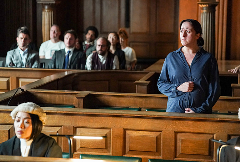 A pregnant woman stands in a courtroom, looking distressed.