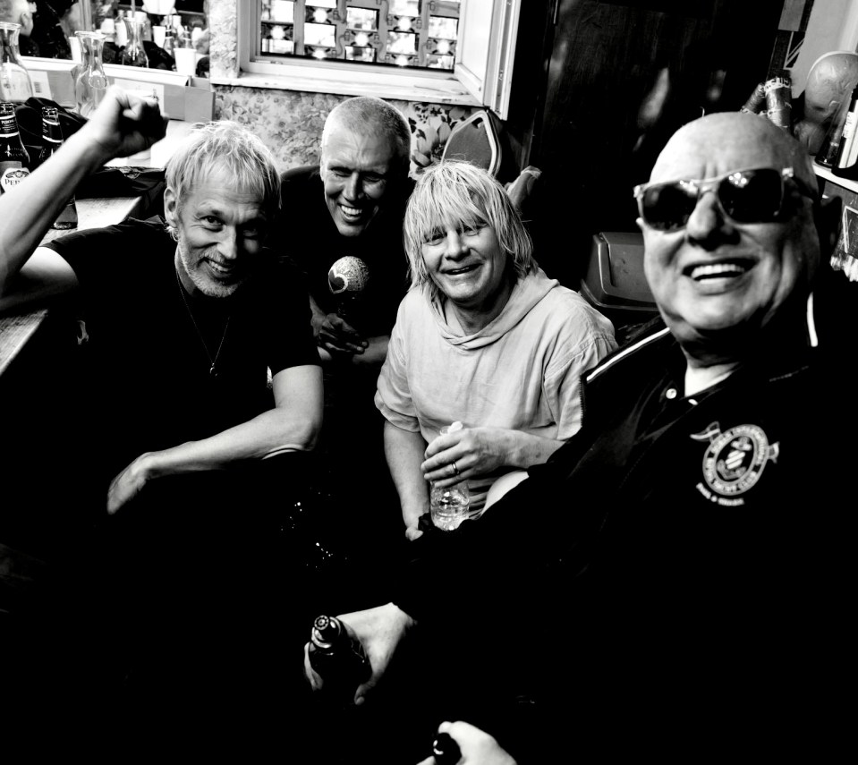 Black and white photo of four men, three of whom are smiling.