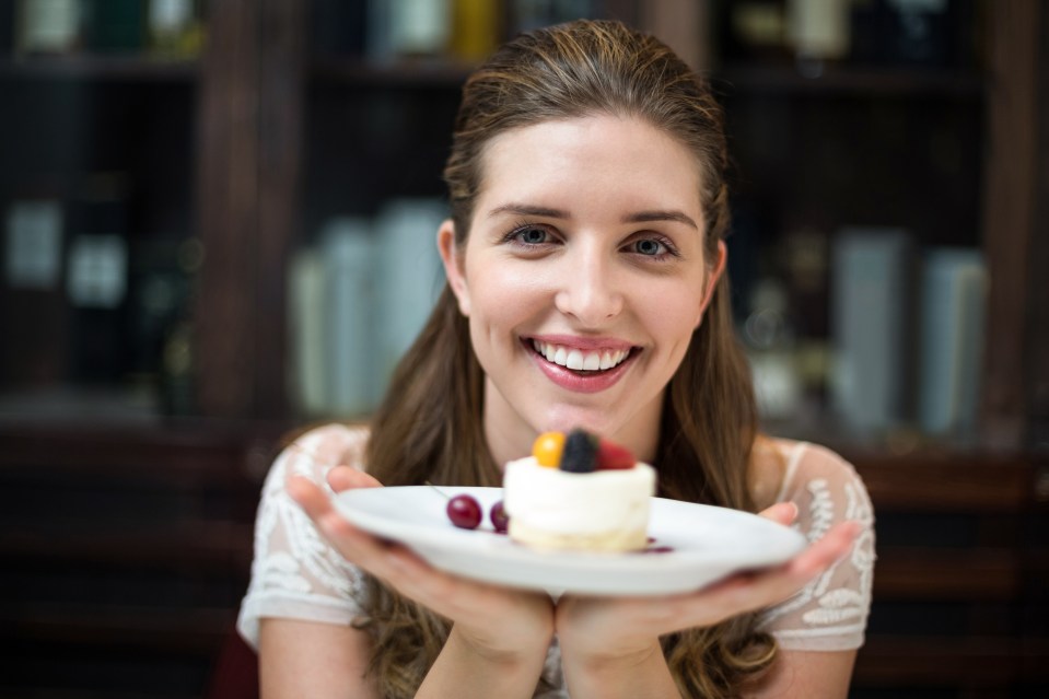 Happy young woman holding a plate with a dessert.