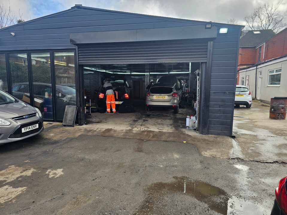 A car repair shop with several cars inside and outside.