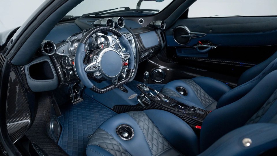 Interior of a blue and carbon fiber Pagani Huayra Roadster.