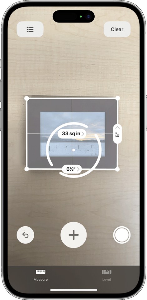 iPhone screen showing the Measure app measuring a framed picture; the picture's dimensions are 6 1/2" by 5" and its area is 33 sq in.
