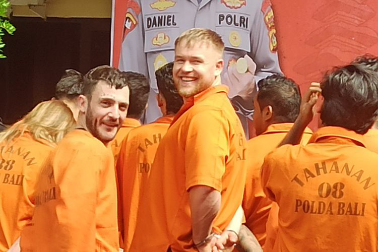 Three British tourists in orange prison jumpsuits at a press conference.