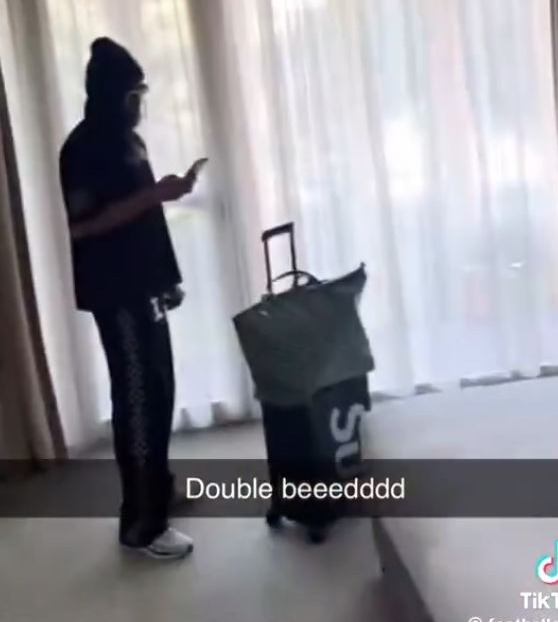 A person with a suitcase in a hotel room.