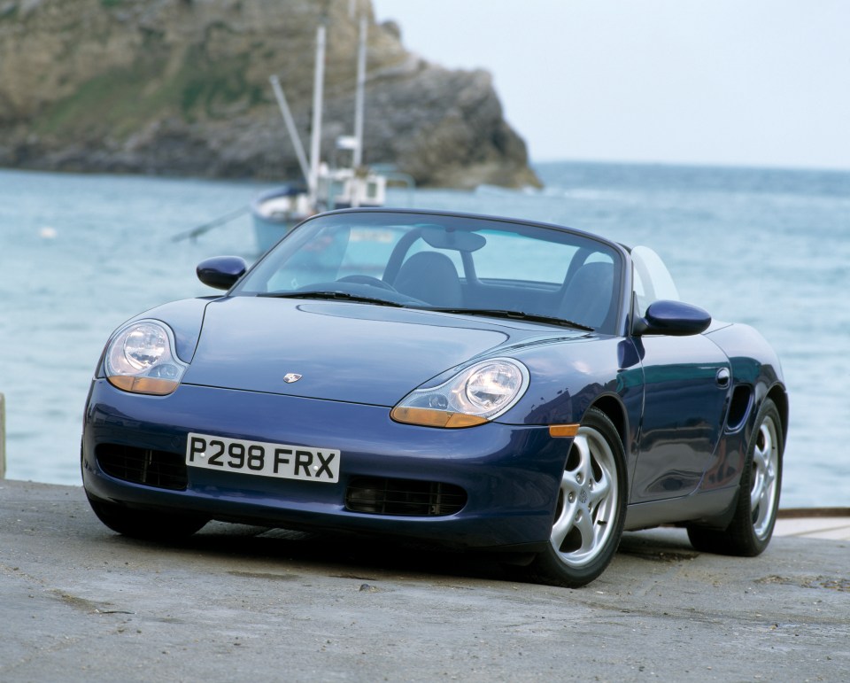 Blue Porsche Boxster parked by the sea.