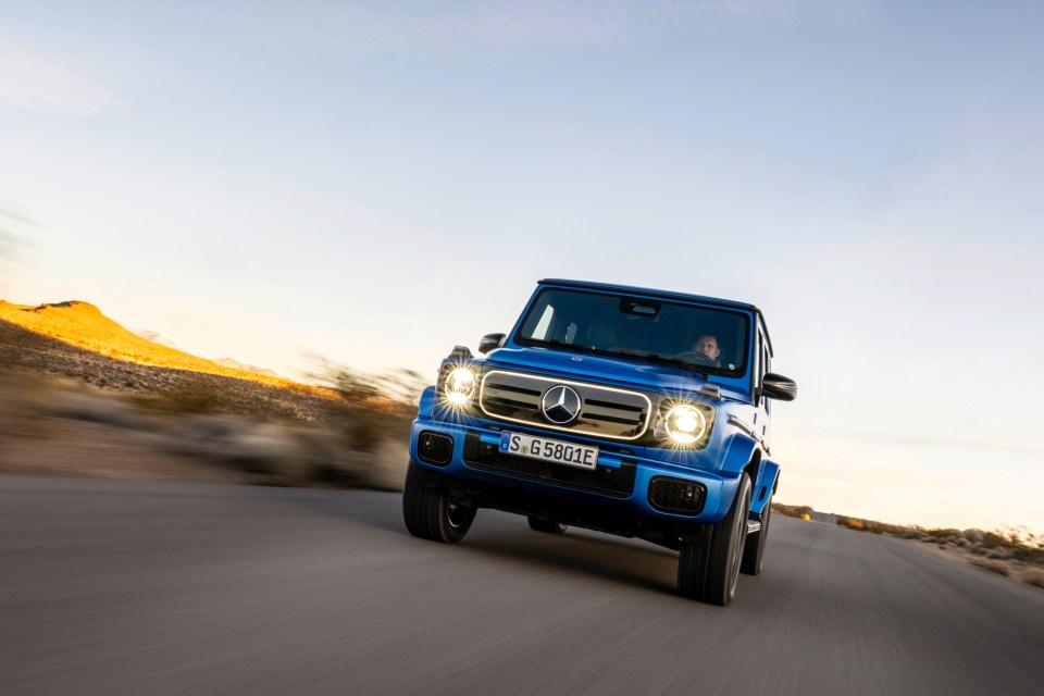 Blue Mercedes-Benz G580 driving on a desert road.