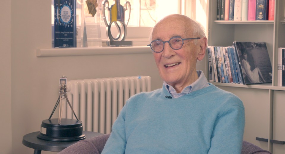 Smiling older man in a light blue sweater.