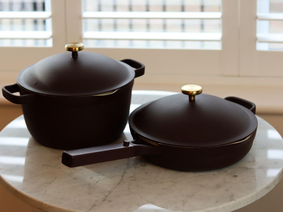 Dark brown pot and pan set on a marble table.