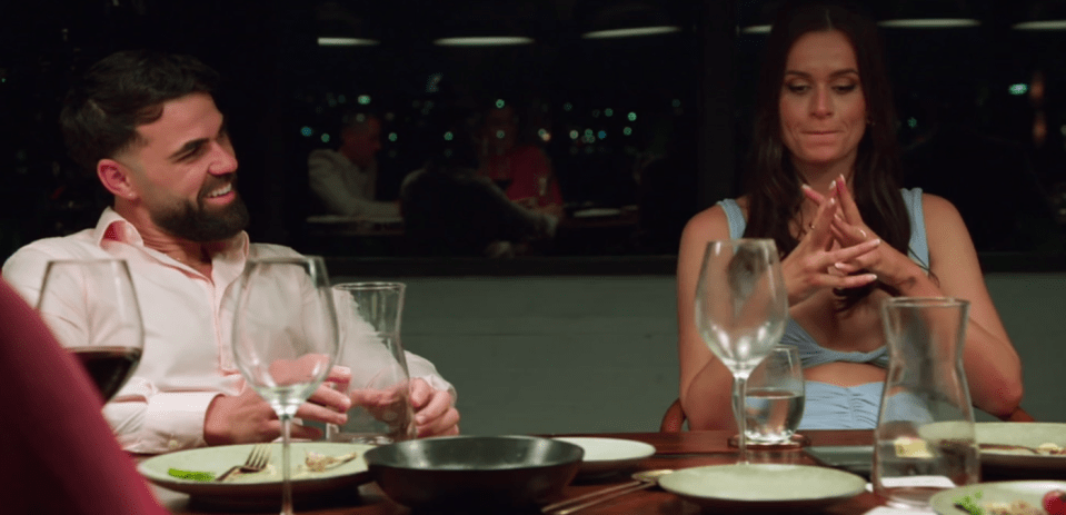 Screenshot of a man and woman sitting at a table, talking.