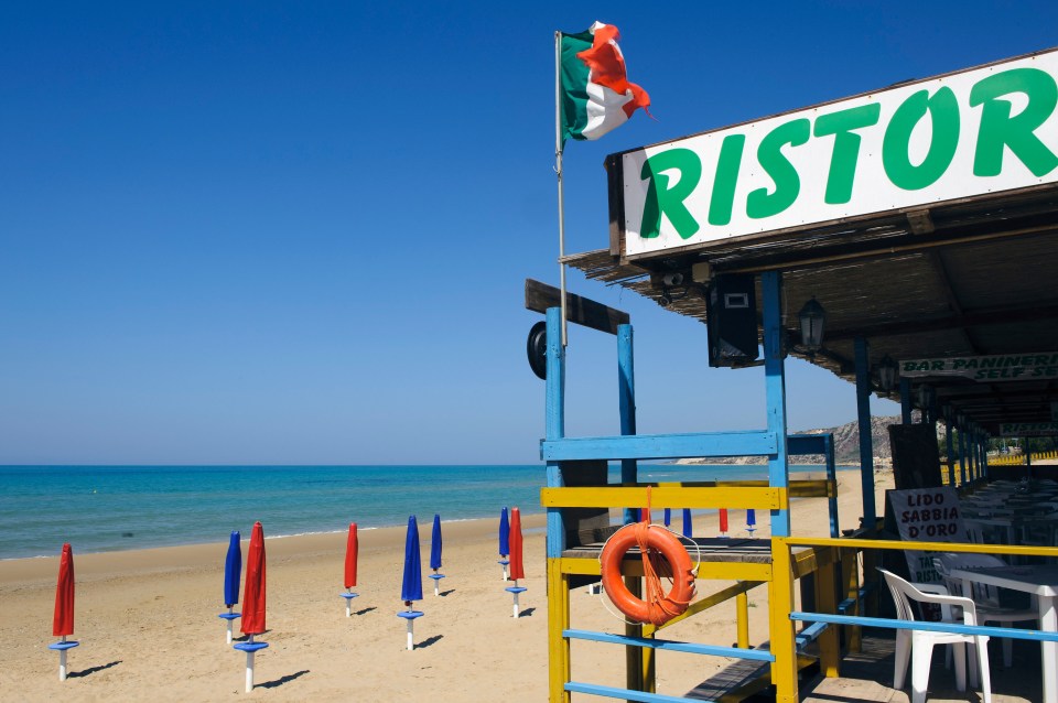 Beach restaurant with Italian flag and lifeguard stand.