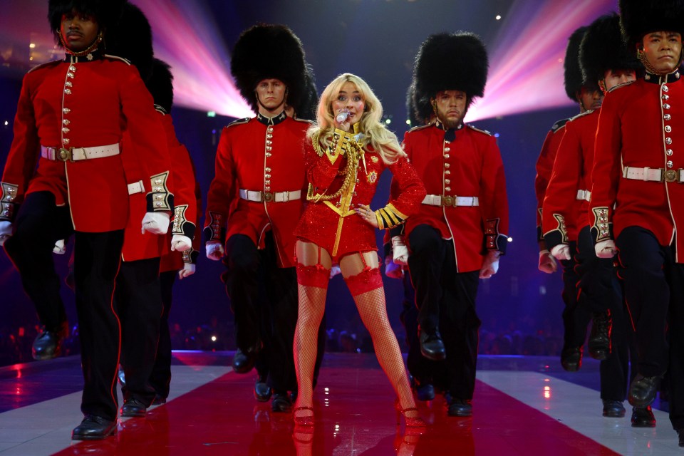 Sabrina Carpenter performing onstage at the BRIT Awards 2025, surrounded by guards in red uniforms.