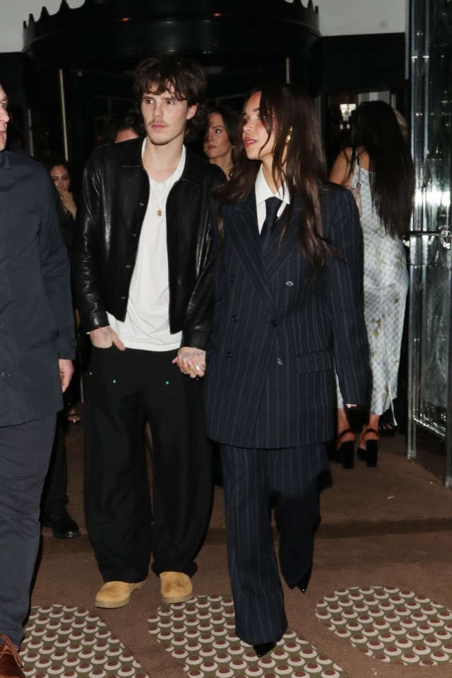 Cruz Beckham and a woman in a pinstripe suit at a party.