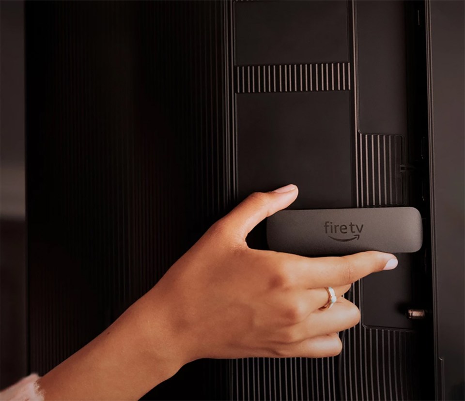 Hand inserting a Fire TV stick into a television.