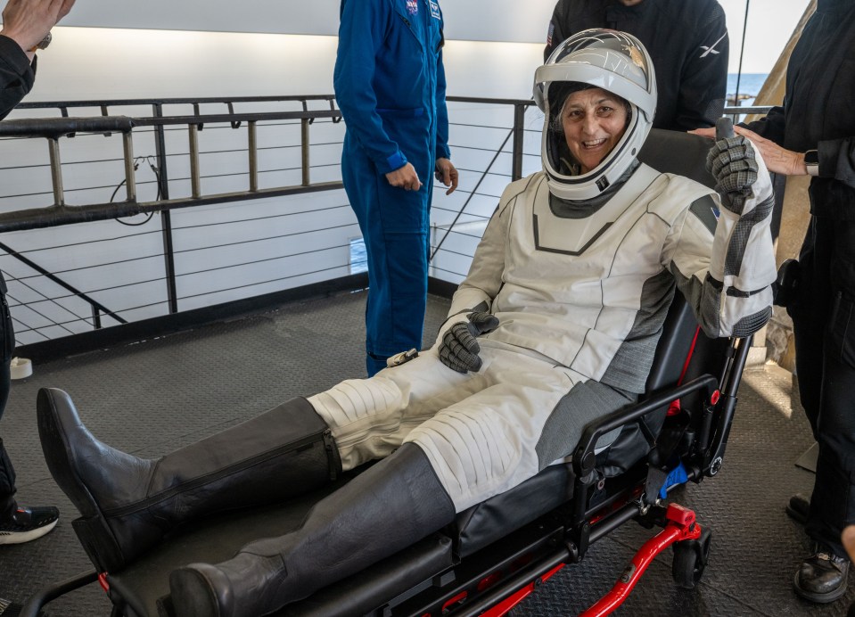 Astronaut Suni Williams gives a thumbs-up while being helped from a SpaceX Dragon spacecraft.