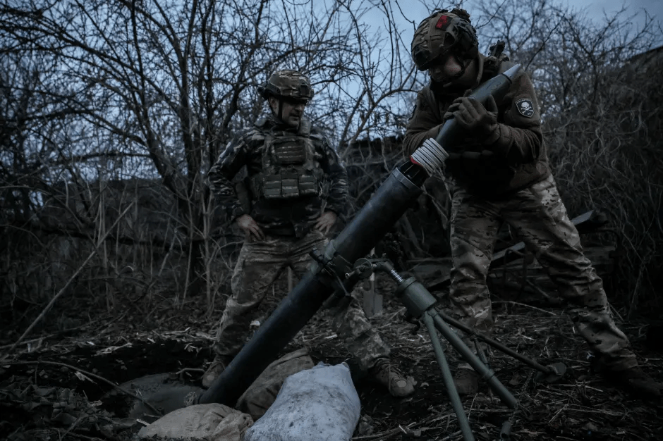 Two soldiers loading a mortar.
