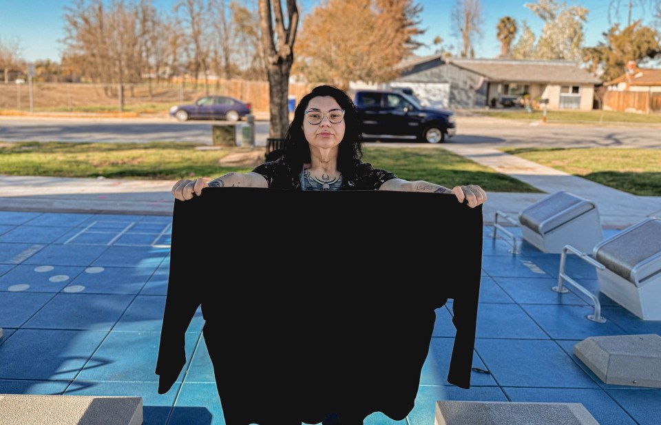 Woman holding up a size 7XL shirt after significant weight loss.