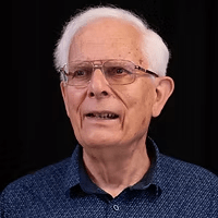 Portrait of an older man with white hair and glasses.