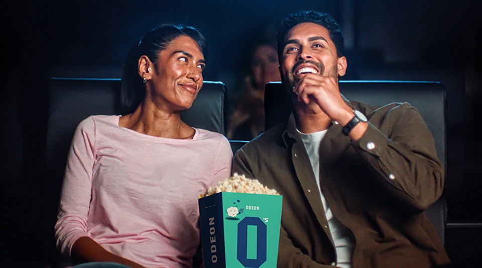Couple enjoying a movie and popcorn at the cinema.