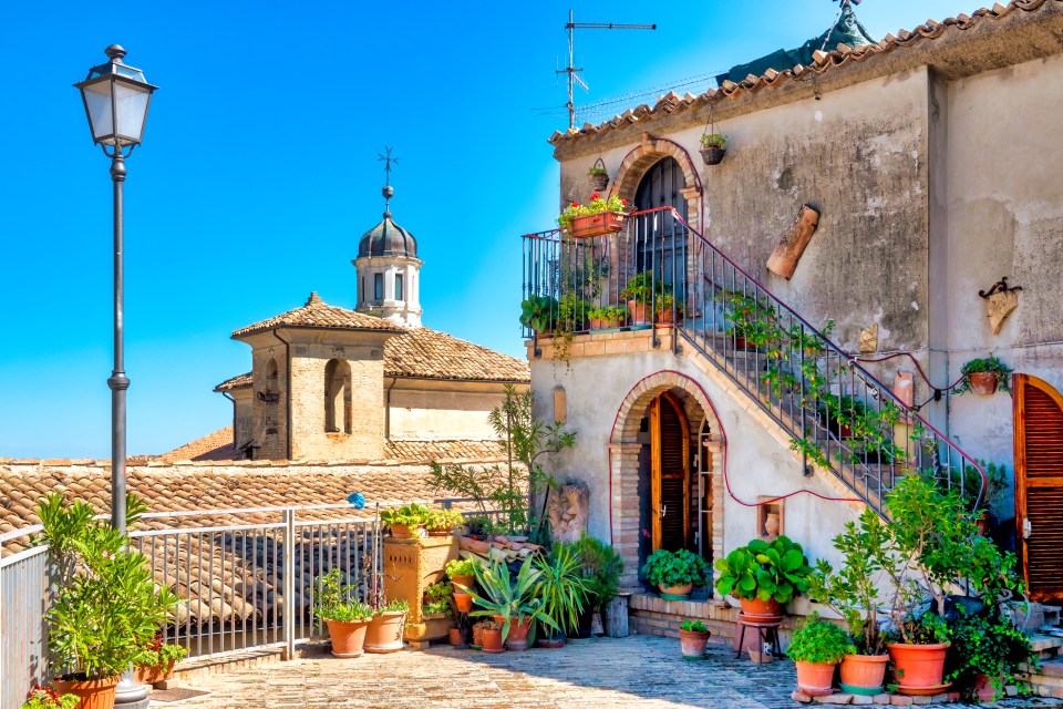 View of rooftops and a building with potted plants in the Castello district of Penne, Italy.