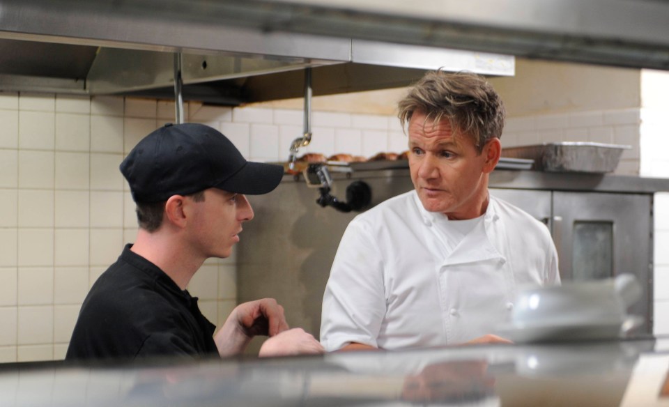 Chef Gordon Ramsay talking to a restaurant worker in a kitchen.