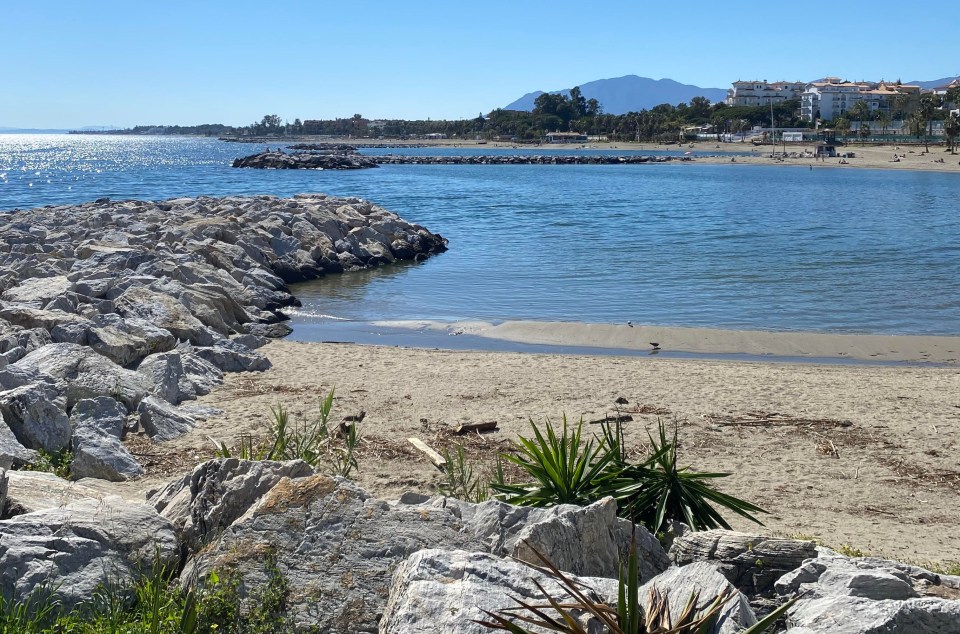 Beach scene with rocky shoreline and calm water.