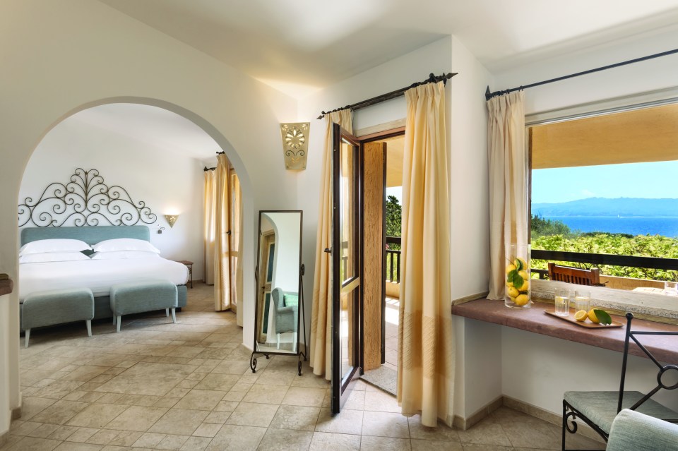 Hotel bedroom with a bed, patio access, and ocean view.