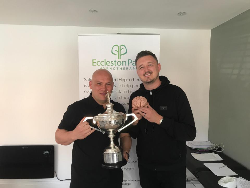 Two men holding a trophy and a model of a brain.
