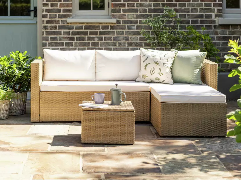 Rattan garden furniture set with cushions and coffee table.