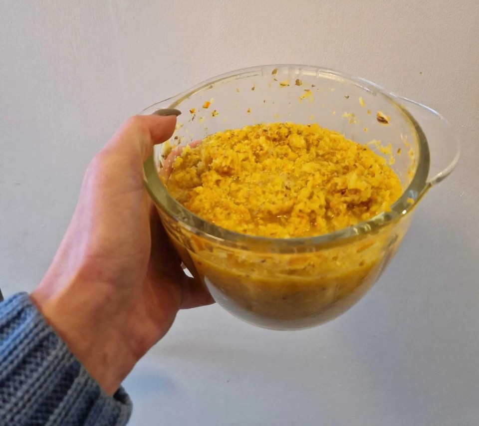 Hand holding a bowl of ginger shot.