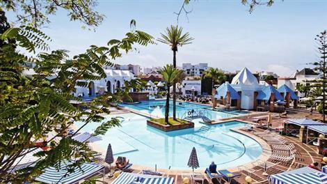 Beach resort with large pool and surrounding buildings.