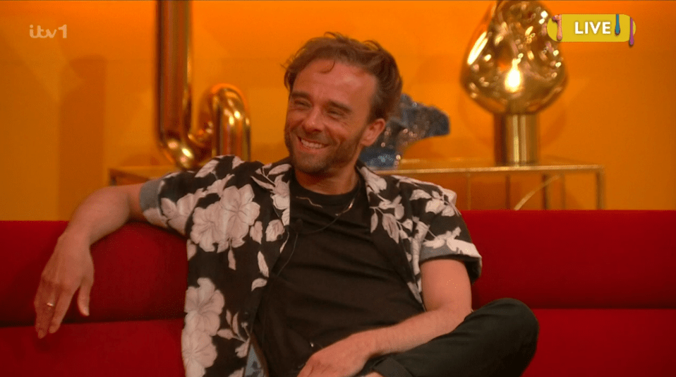Man smiling on a red couch.